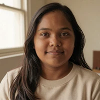 Priya, a little person community member, smiling softly in warm window light