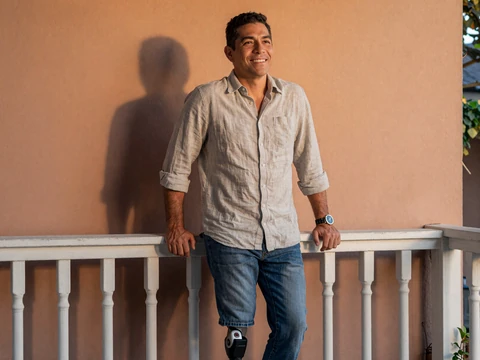 Luis, a Latino man with a prosthetic leg smiling on a sunlit porch
